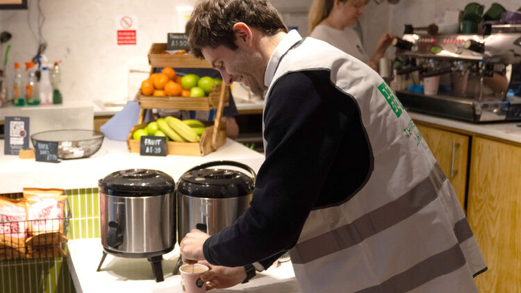 Een afbeelding van een lachende man met een kopje in zijn hand.