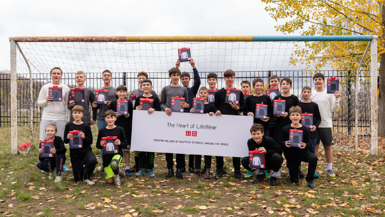 Groepsfoto van een groot aantal kinderen met HEATTECH-producten voor een voetbaldoel.