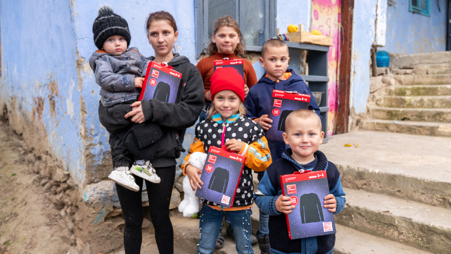 Afbeelding van een volwassene en vijf kinderen die HEATTECH-producten vasthouden en poseren voor een foto.