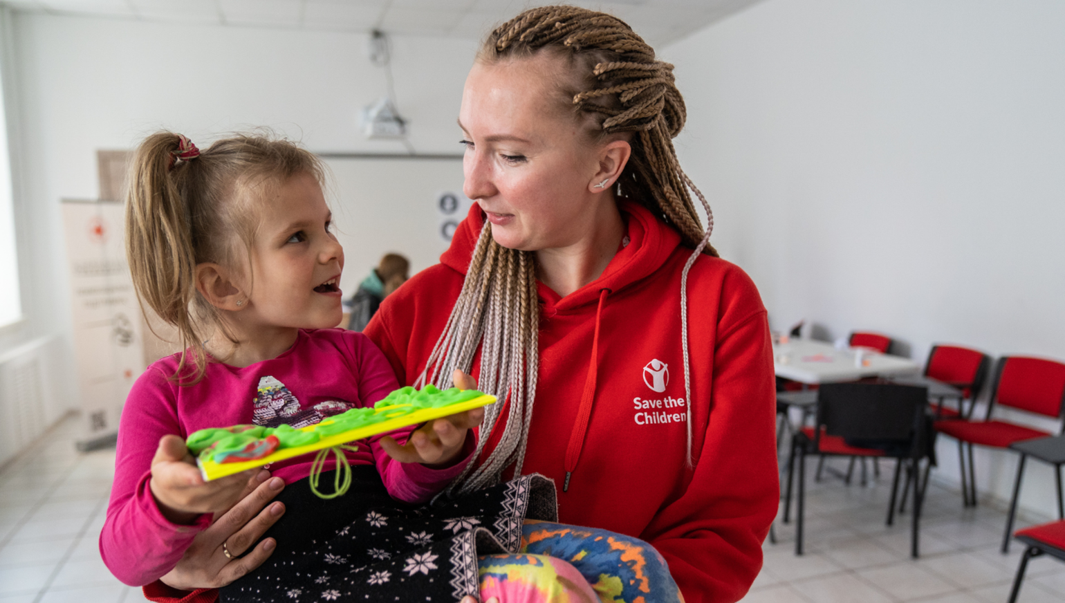 Olga Shults, programmamanager bij Save the Children, houdt een meisje vast in een ‘Child Friendly Space’ in Oekraïne
