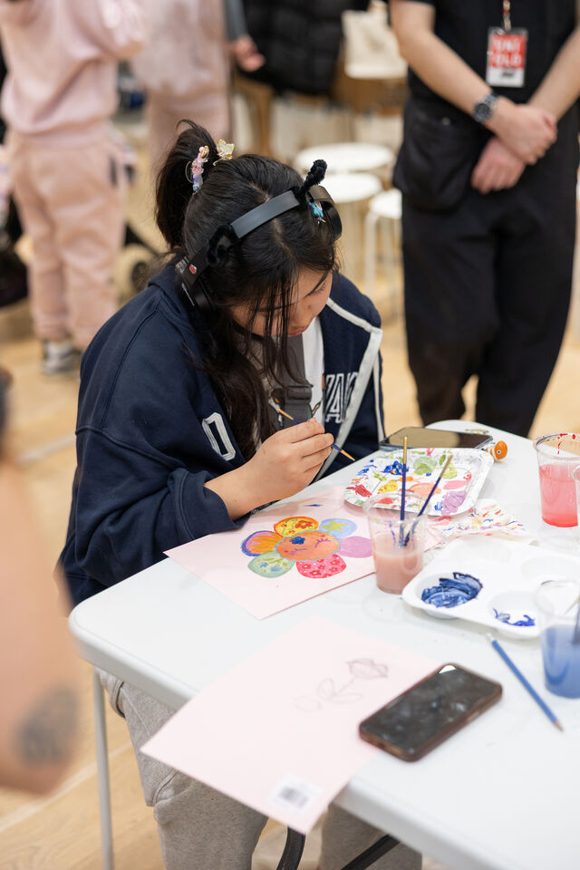 young female in a blue hoodie painting a picture