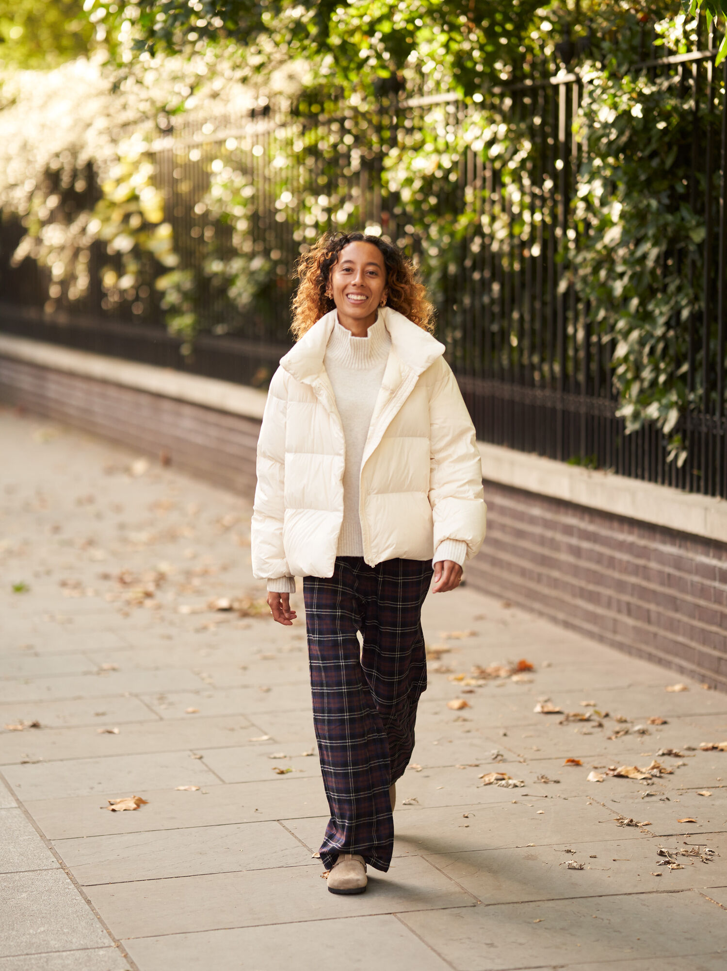 Model in weißer Daunenjacke und schwarzer Hose