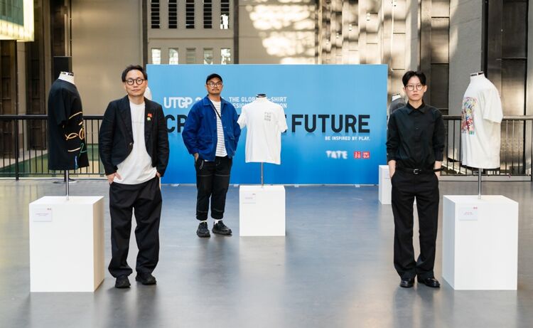 the winners stand next to their winning designs on T-shirts, displayed on mannequins