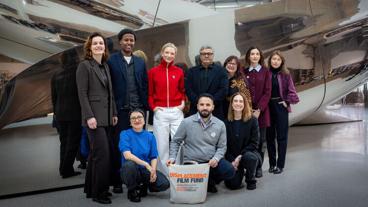 A group photo of Cate Blanchett and associates holding bags labelled 