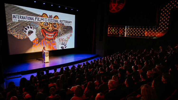 An image of a person giving a speech on stage, with the international film festival logo projected on a large screen behind them.