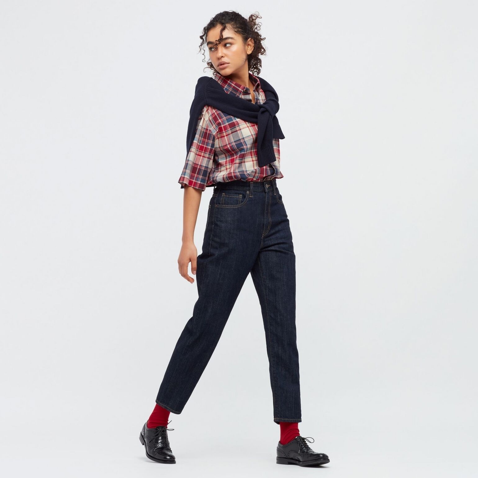 woman wearing UNIQLO mom jeans with checked shirt and jumper draped over shoulders, burgundy socks and brogues