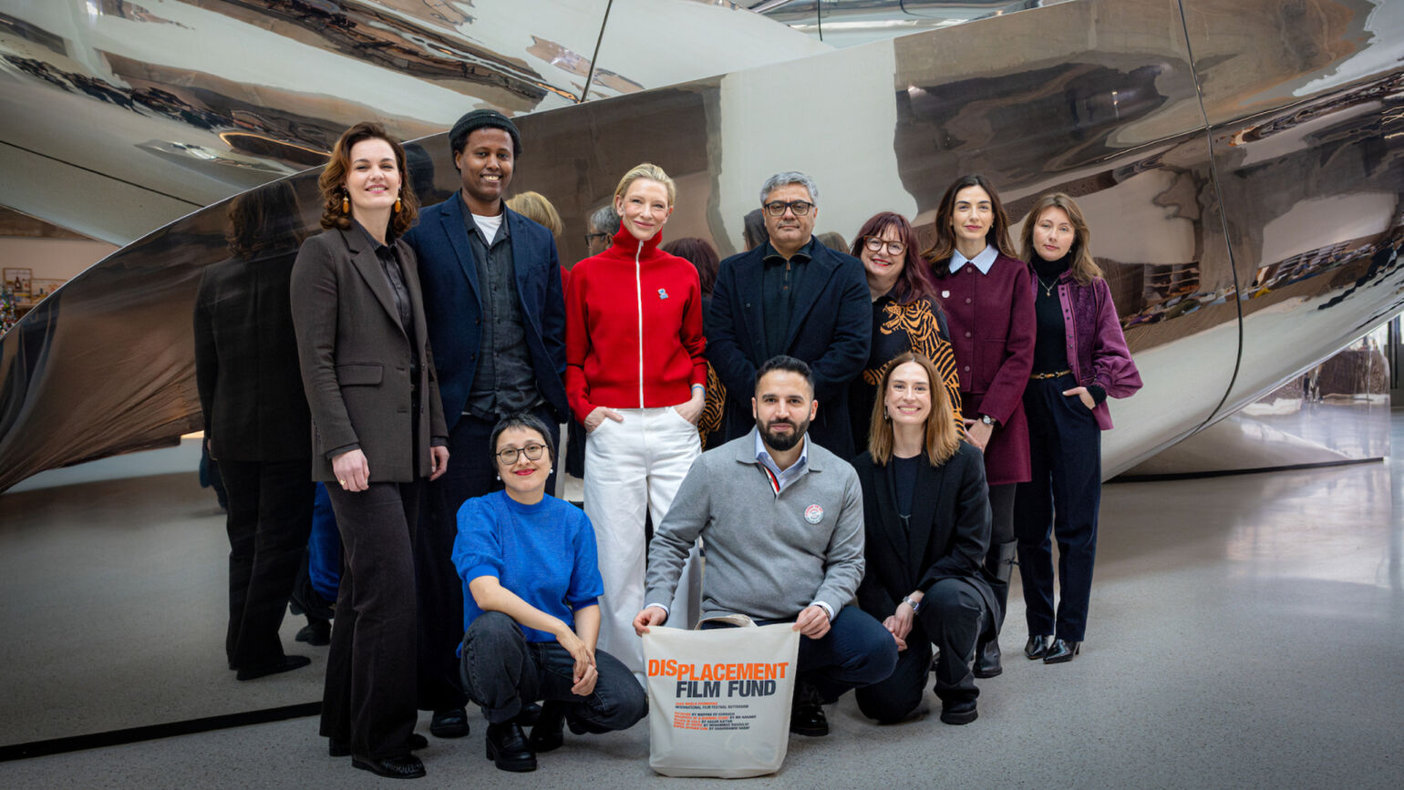 A group photo of Cate Blanchett and associates holding bags labelled 