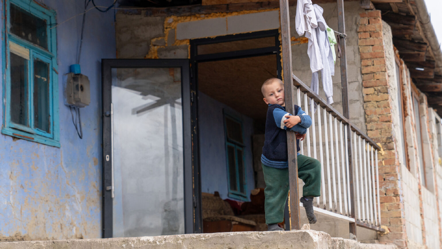 Un enfant appuyé contre un pilier regarde l