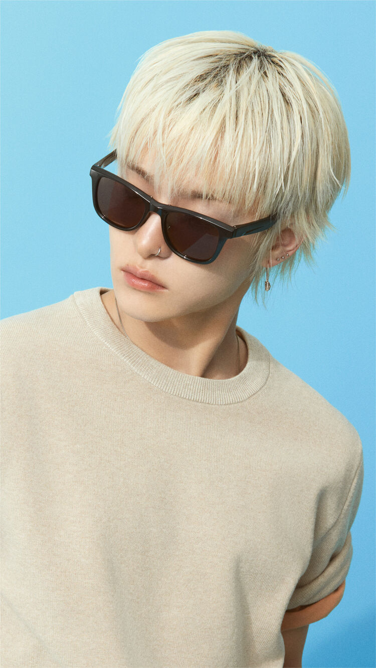 A close-up image of JIHOON wearing Wellington Folding Sunglasses, looking sideways with a cool expression.