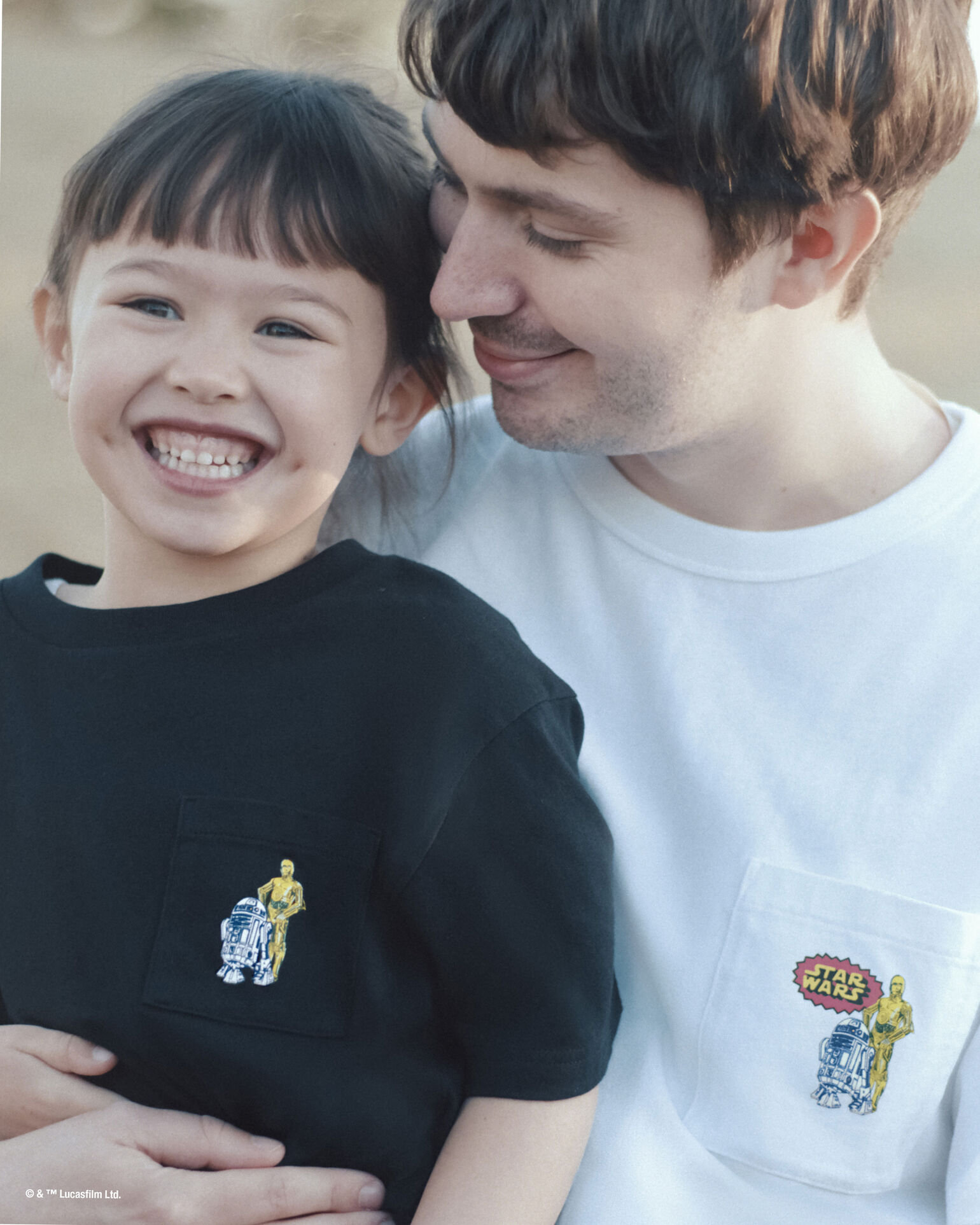 A heartwarming photo of Jaimy gently hugging Daisy, both wearing different colored T-shirts with Star Wars characters R2-D2 and C-3PO designed on the pockets.