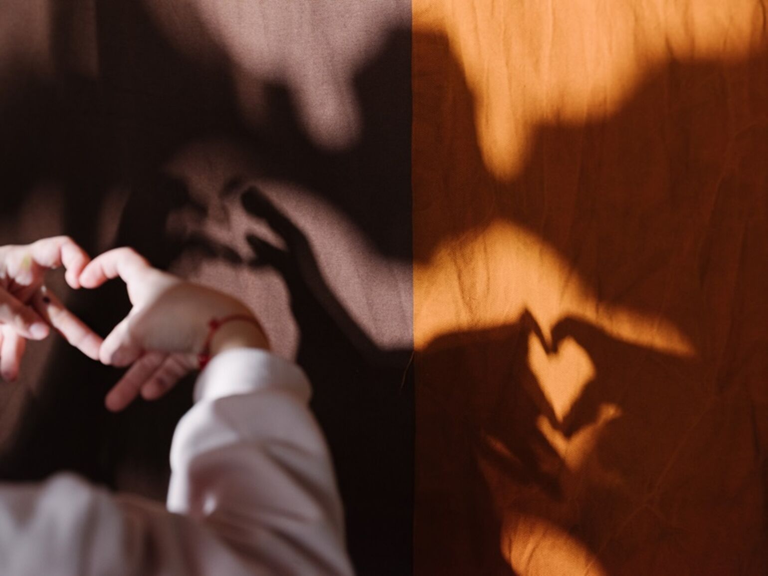 A child creates a heart-shaped shadow in a pop up studio at a Save the Children Counselling Hub © Olivia Arthur / Magnum Photos