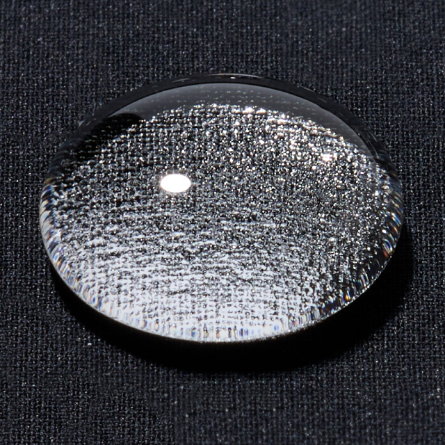 Photo of water droplets on the surface of seamless down fabric. The drops form bubbly beads due to the cushion of air between them and the fabric.