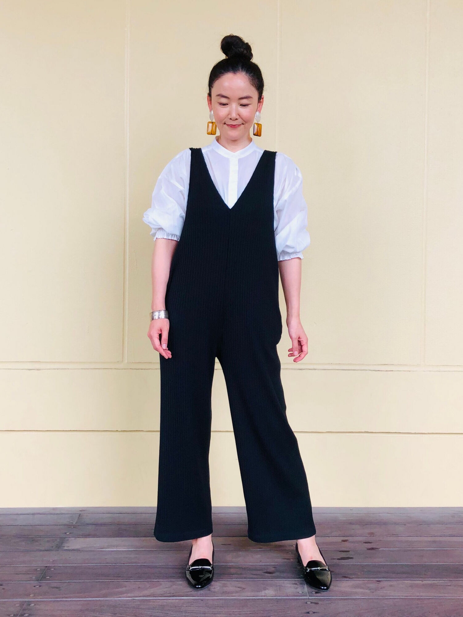 黒のサロペットにボリューム袖がポイントのブラウスを合わせたレディースコーデ。