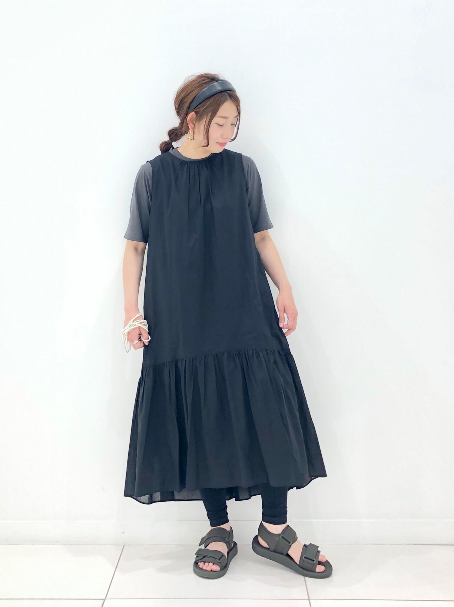 黒のティアードワンピースにTシャツやレギンスをレイヤードしたレディースコーデ。