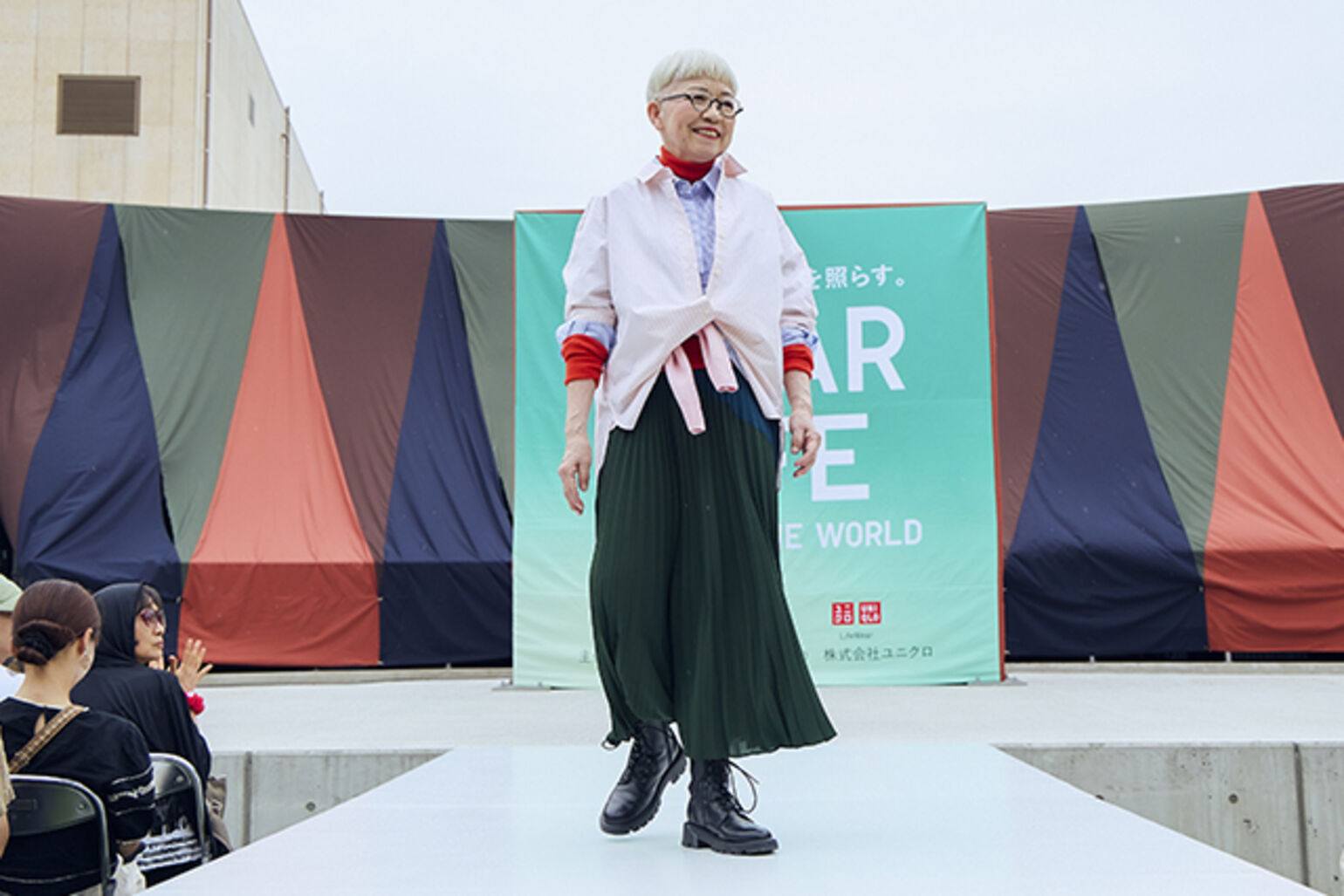 メリノリブタートルネックセーター、コットンシャツ/ストライプ、コットンコクーンシャツ/ストライプ、カシミヤクルーネックセーター、プリーツロングスカートを着た女性