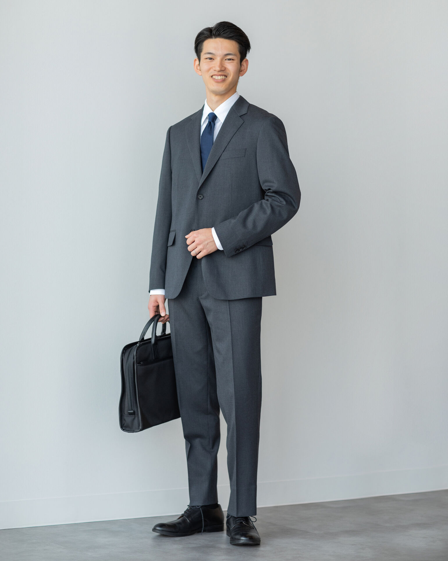 カバンを持ってこちらを見つめるスーツを着たShuiさんの画像