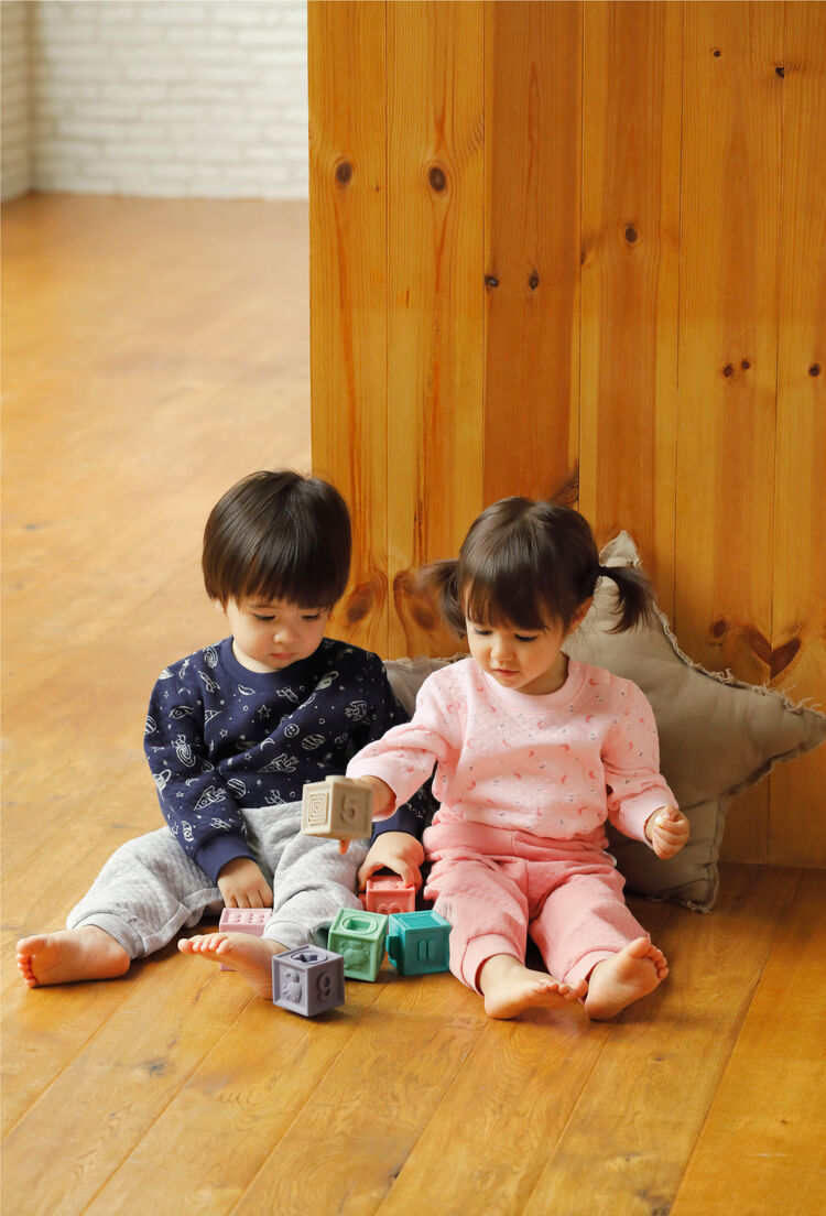 ネイビーのJoy of Printキルトパジャマを着ている男の子とピンクのJoy of Printキルトパジャマを着ている女の子