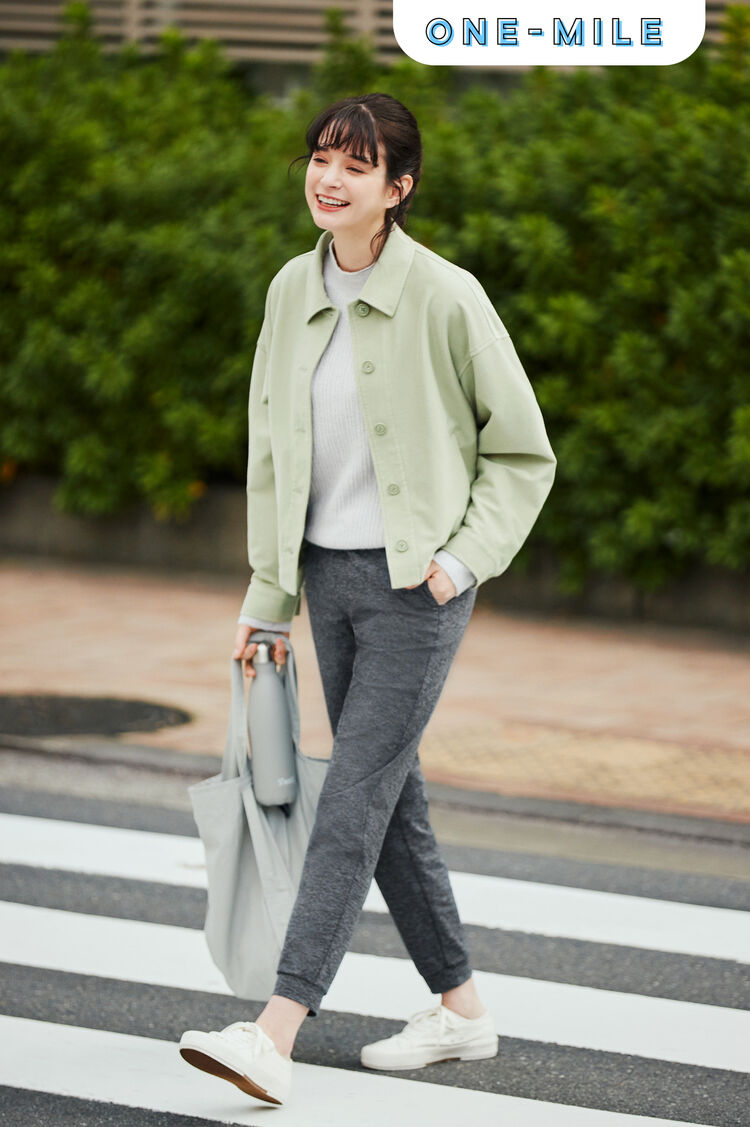 黄緑のジャージーリラックスジャケットとグレーのライトスフレヤーンモックネックセーターにグレーのウルトラストレッチアクティブジョガーパンツの女性