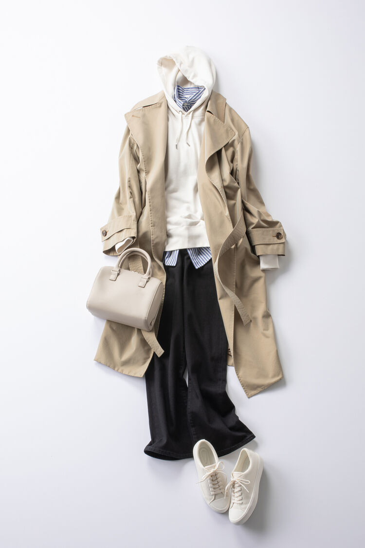 シャツをレイヤードした白パーカの上にベージュのトレンチコートを羽織ったレディースコーデ。