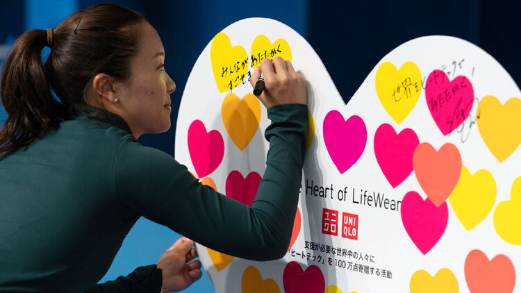 An image of Kurumi Nara writing a message on a heart board.