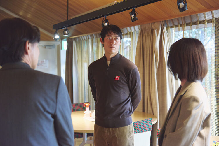 An image of Kei Nishikori in UNIQLO apparel, facing and listening to officials in a room.
