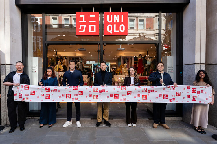 A scene from the opening ceremony at the newly reopened UNIQLO Covent Garden store, where Roger Federer, Clare Waight Keller, and local staff members stand in a row to cut a ribbon adorned with UNIQLO logos.