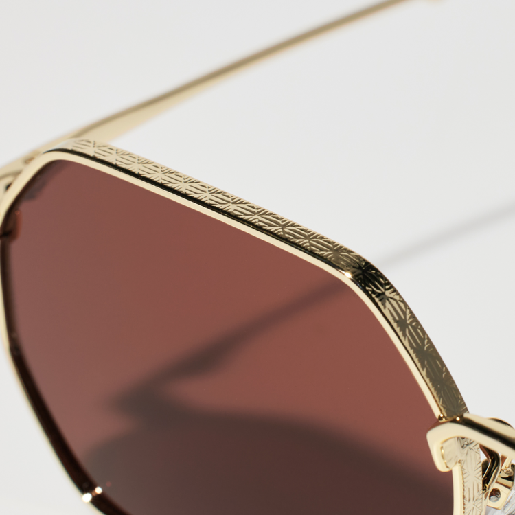 A close-up image highlighting the intricate engraved patterns (milgrain) on the upper frame of the metal hexagon-type sunglasses.