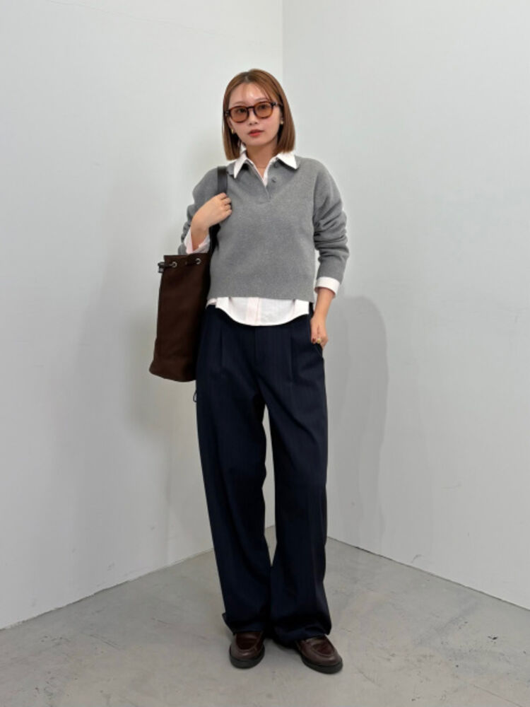 An image of a woman in an elegant full outfit, wearing brown cello-frame sunglasses, a gray knit polo, and navy striped pants.