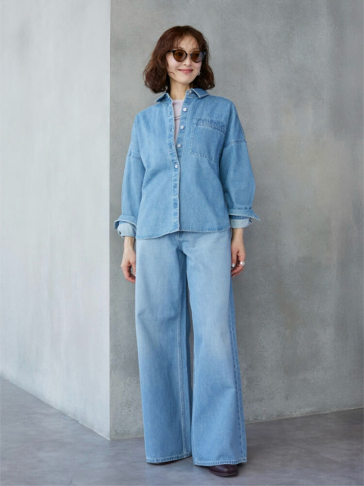 An image of a woman in a denim-on-denim full setup style outfit, wearing brown sunglasses, a denim shirt, and matching denim wide-leg pants.
