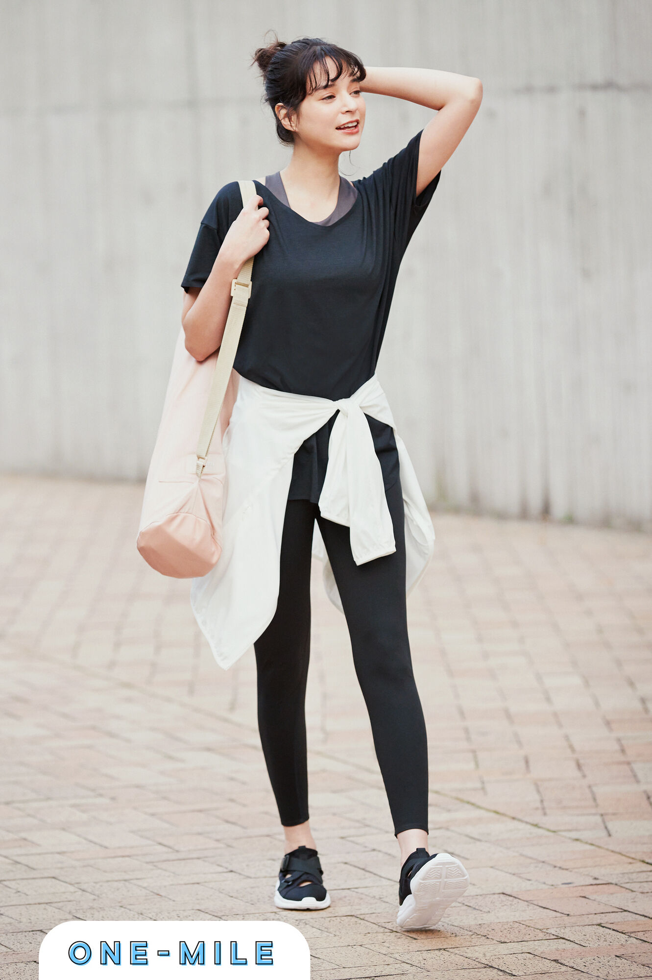 グレーのWワイヤレスブラと黒いエアリズムシームレスＶネックロングＴのレイヤードに黒いレギンスを合わせ腰に白いパーカを巻いた女性