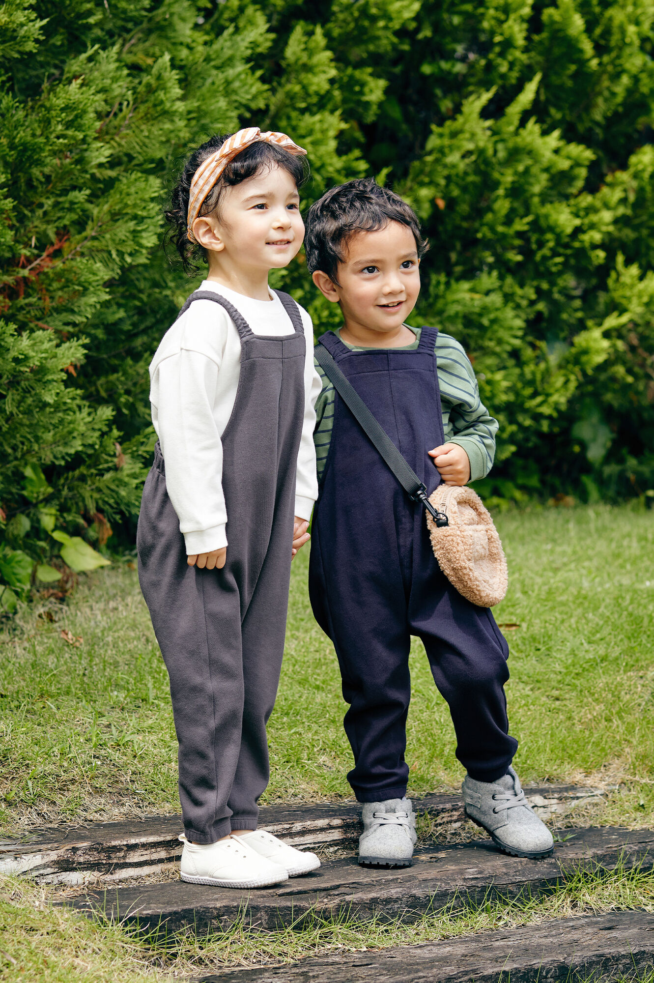 グレーのサロペットパンツと白いソフトタッチコットンクルーTを着た女の子と紺のサロペットパンツとグリーンのソフトタッチコットンクルーTを着た男の子