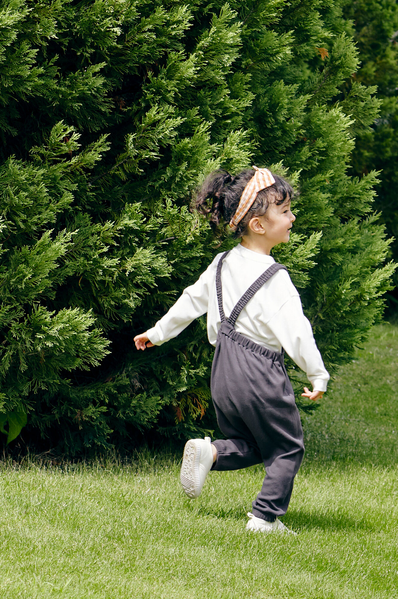グレーのサロペットパンツと白いソフトタッチコットンクルーTを着た女の子の後ろ姿
