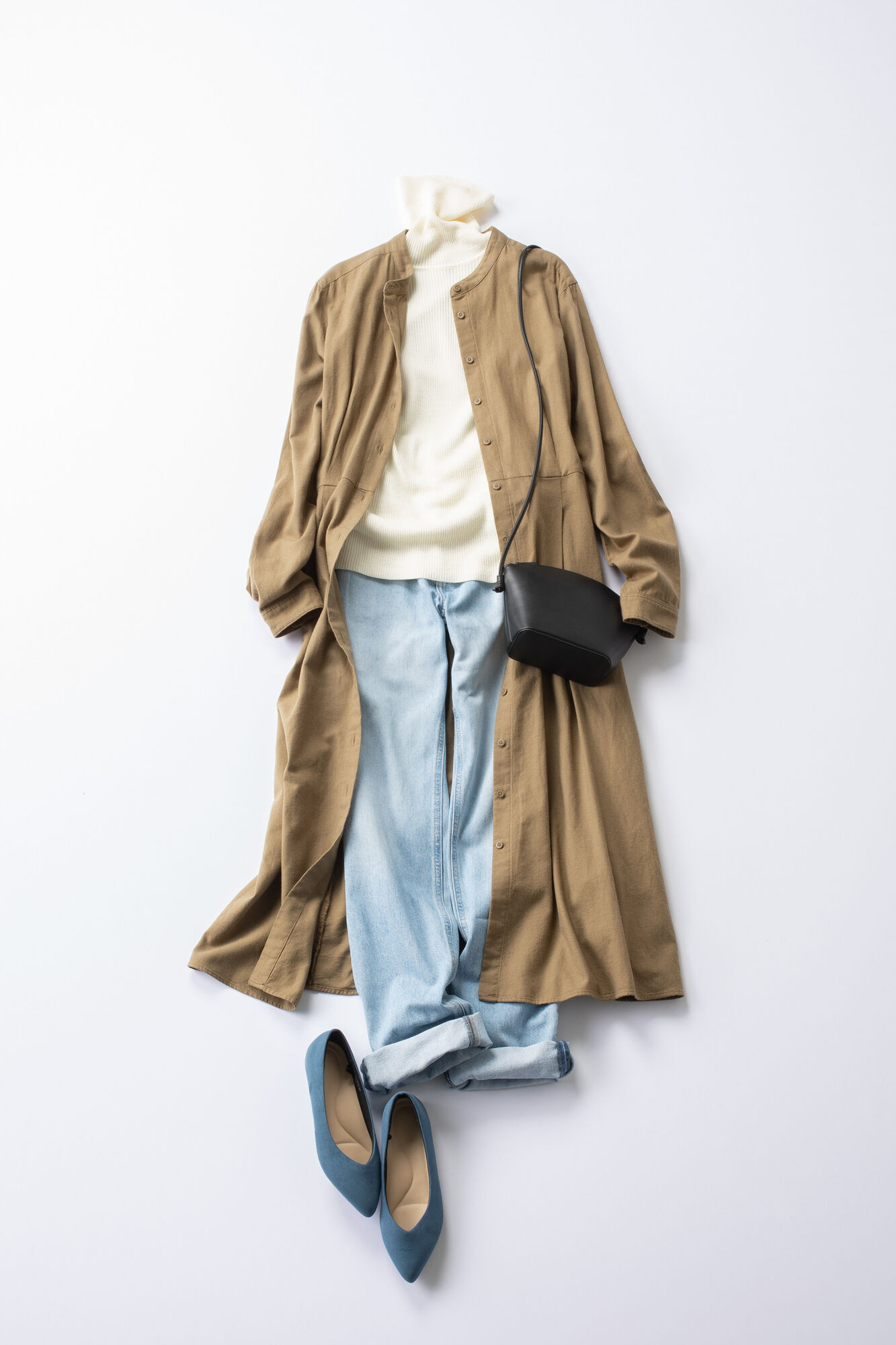 タートルネックのニットとジーンズにベージュのロングシャツワンピースを羽織ったレディースコーデ。