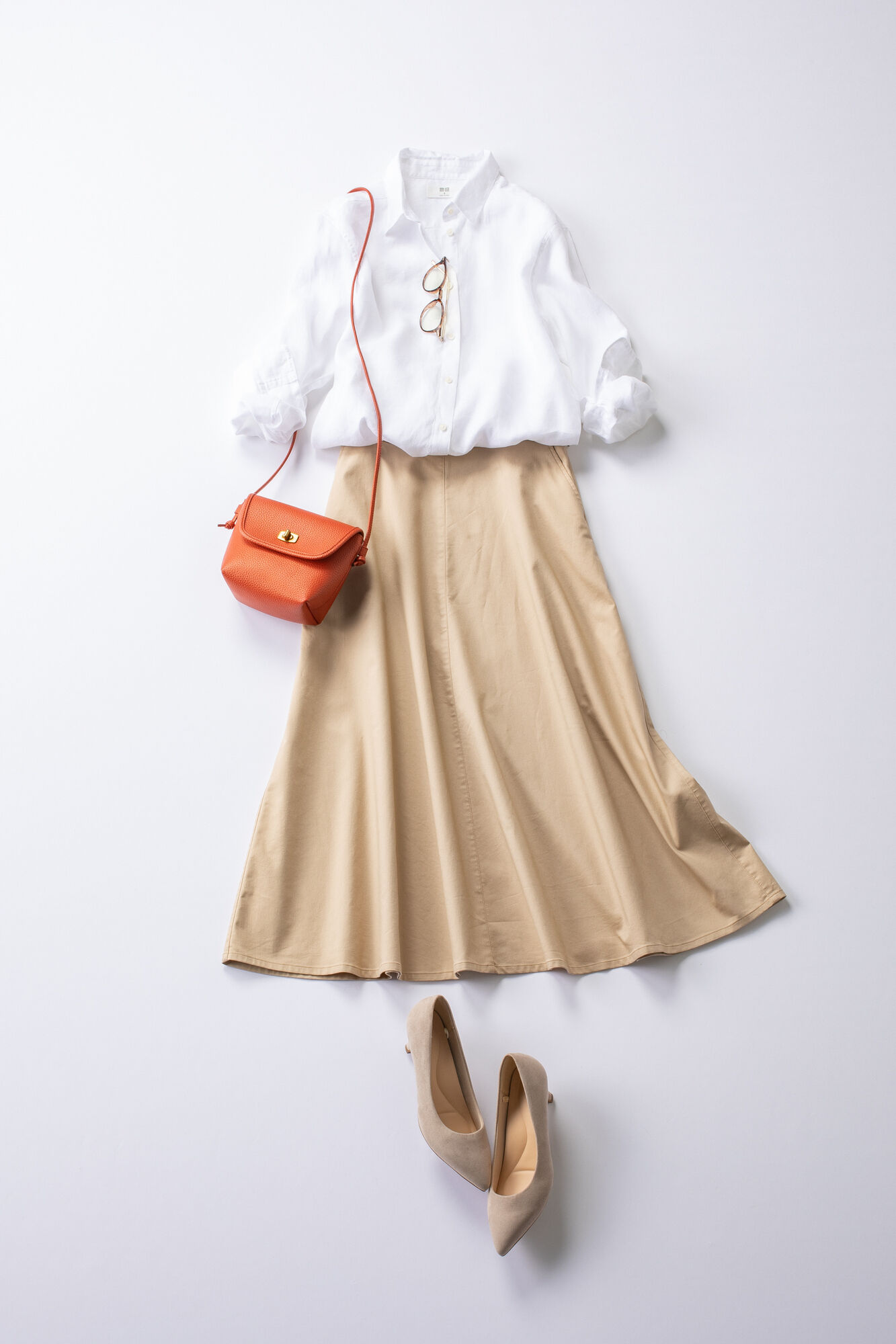 白のリネンシャツにベージュのサーキュラースカートをあわせたレディースの夏コーデ。