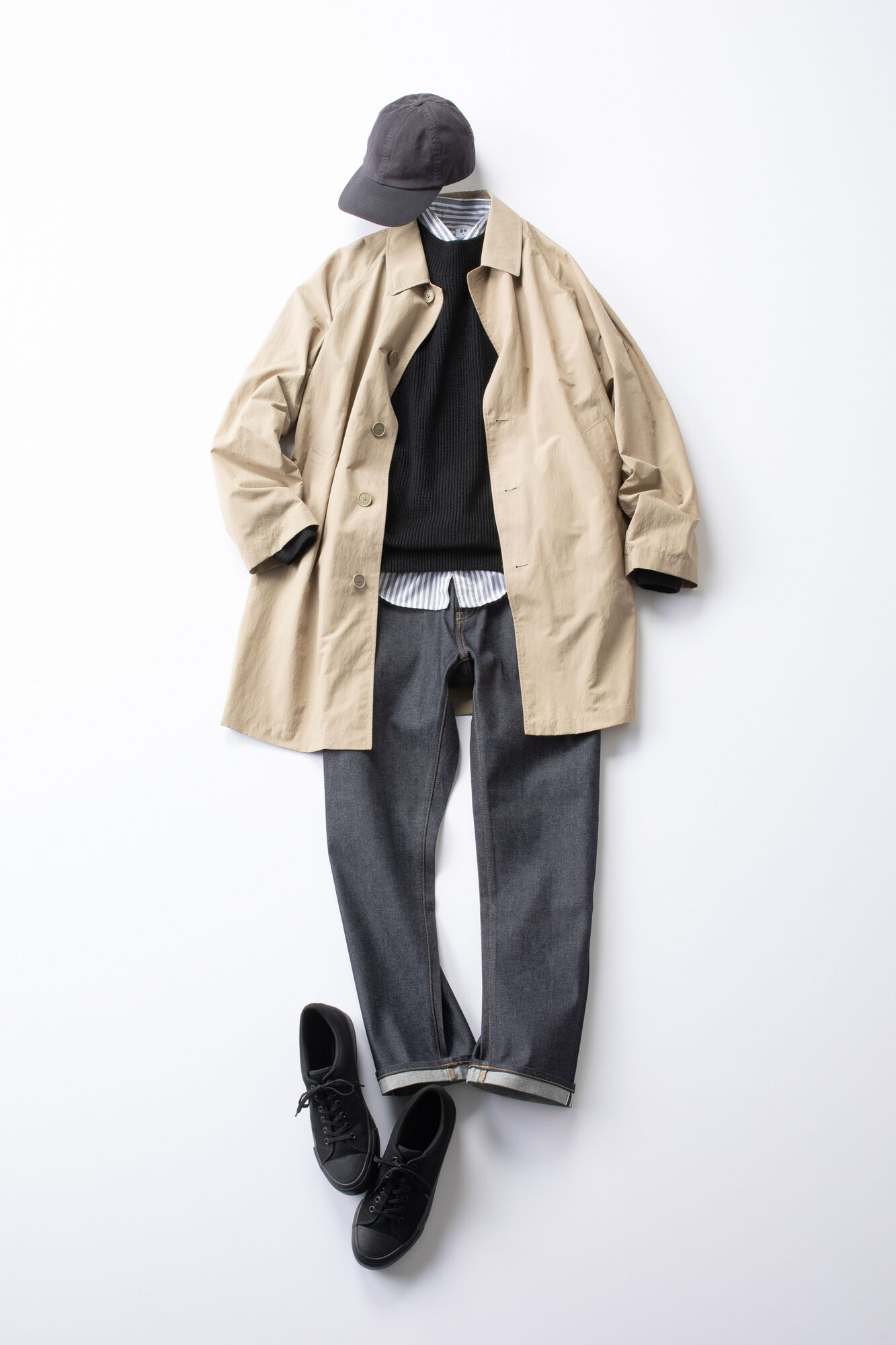 黒のセーターに濃紺のジーンズを合わせ、ベージュのコートを羽織ったメンズコーデ。