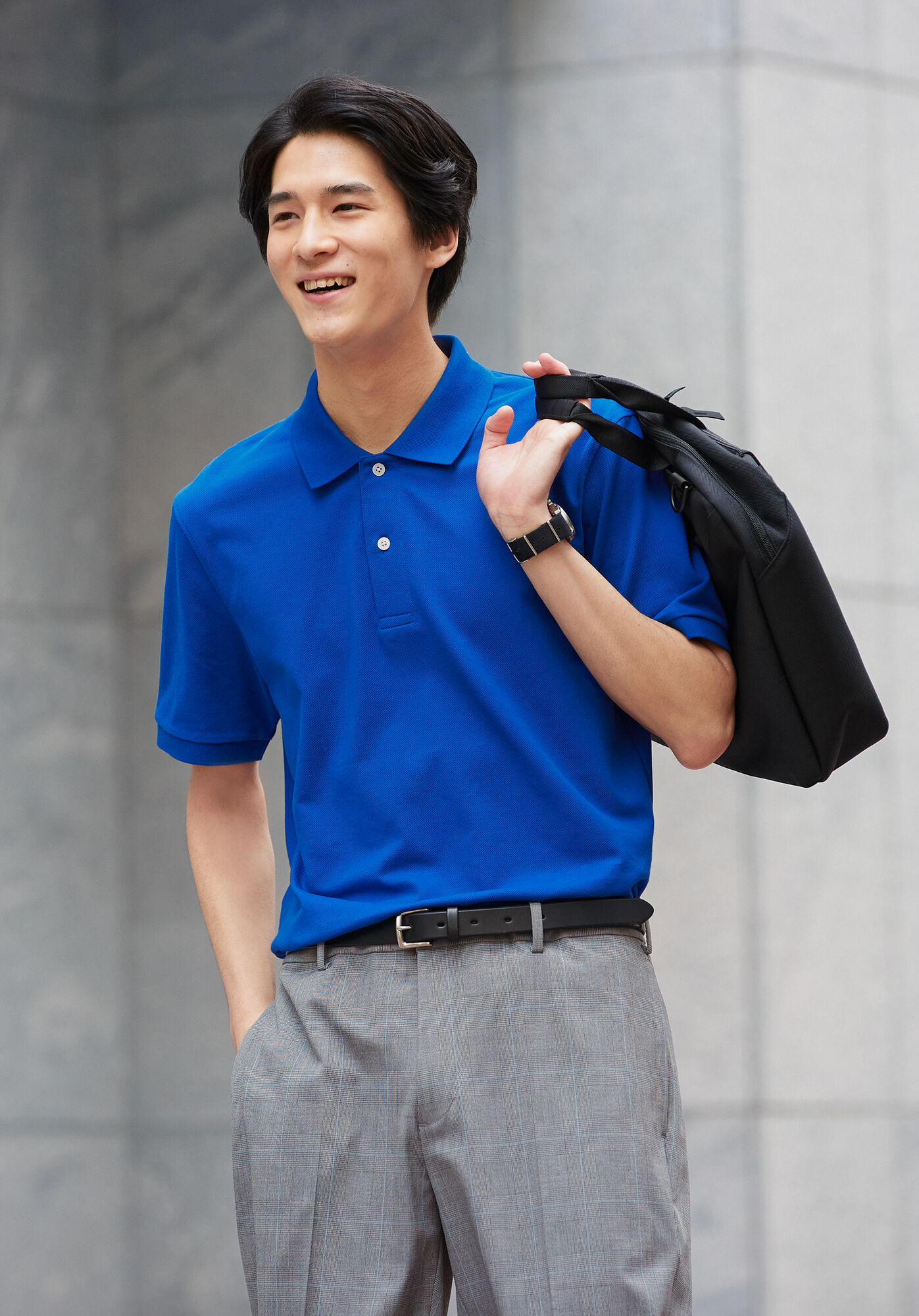 ブルーのドライカノコポロシャツとグレーのスマートアンクルパンツを着た男性