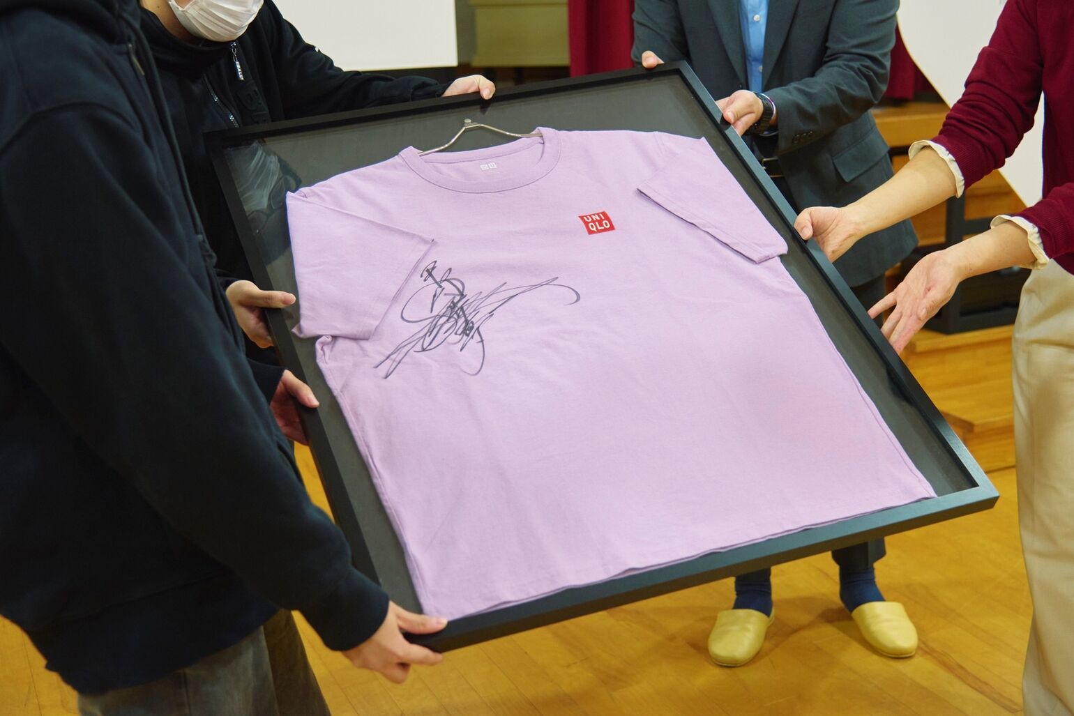 An image of a light purple T-shirt signed by Ayumu Hirano, presented in a frame.