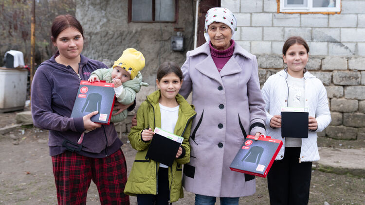 Image of two adults and three children holding HEATTECH products and posing for a photo