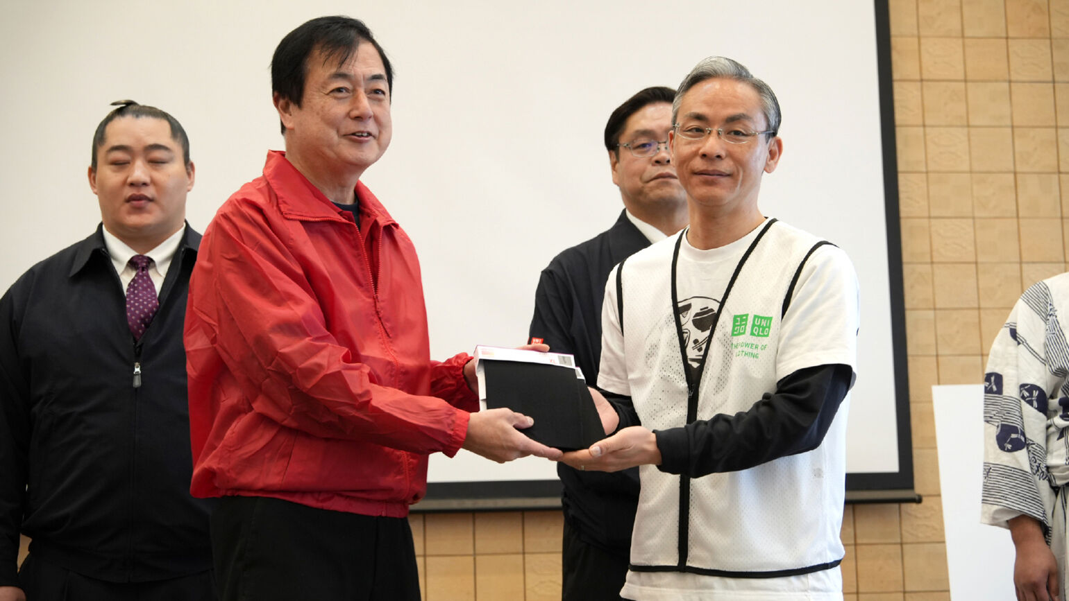 Image of UNIQLO COO Tomohiko Sei and Nomi City Councilor Sakujiro Tanaka holding HEATTECH products
