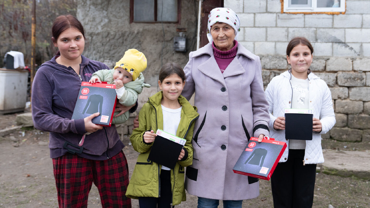Image of two adults and three children holding HEATTECH products and posing for a photo