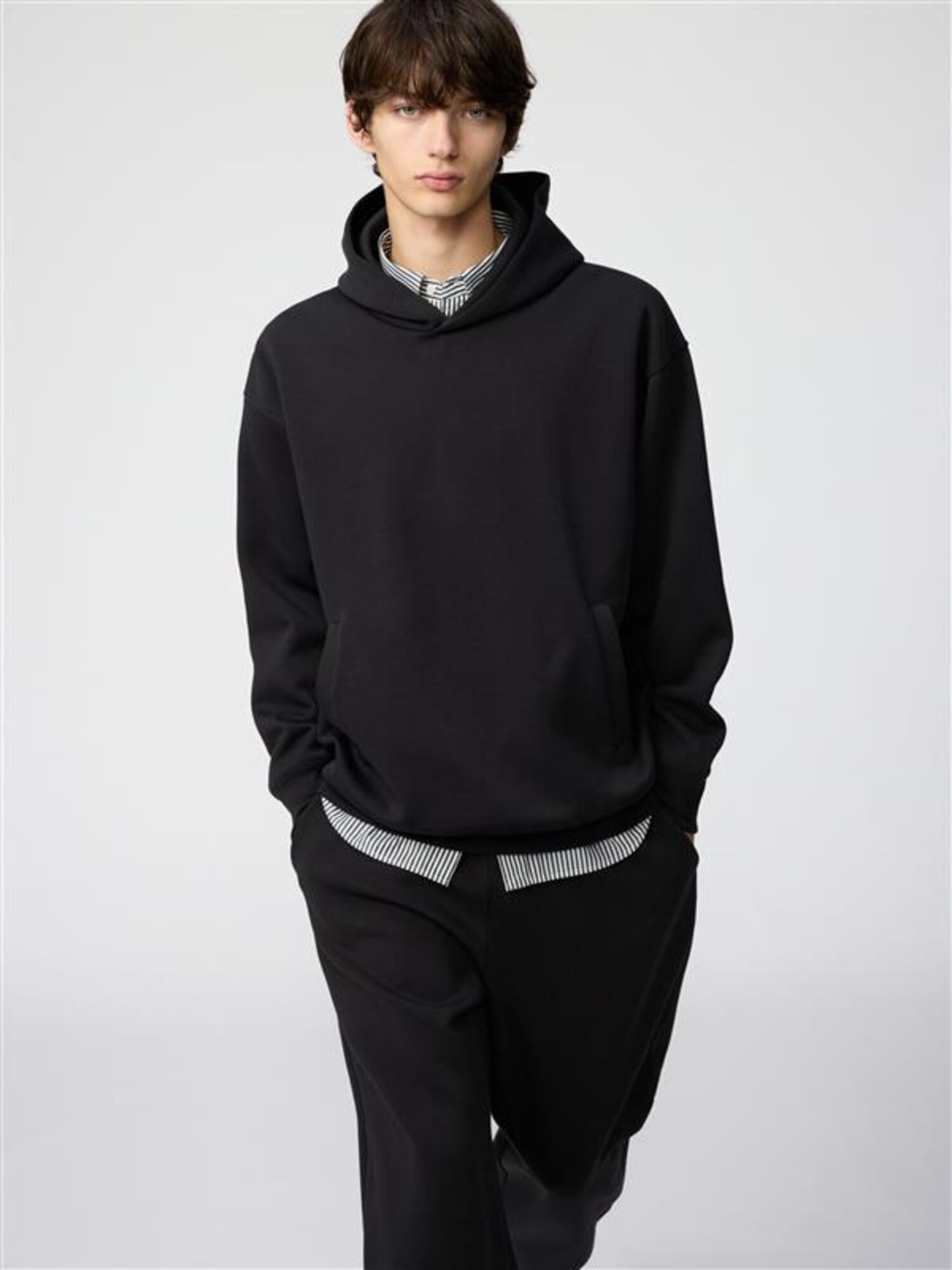 ผู้ชายสวมเสื้อฮู้ดกันหนาวสีดำของ UNIQLO