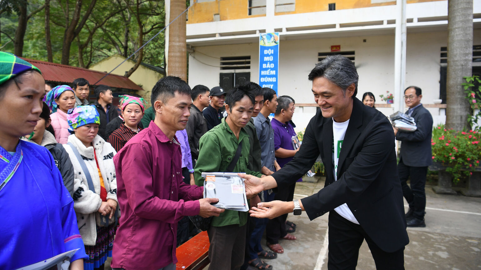 An image of a UNIQLO representative smiling and handing HEATTECH to a local man.