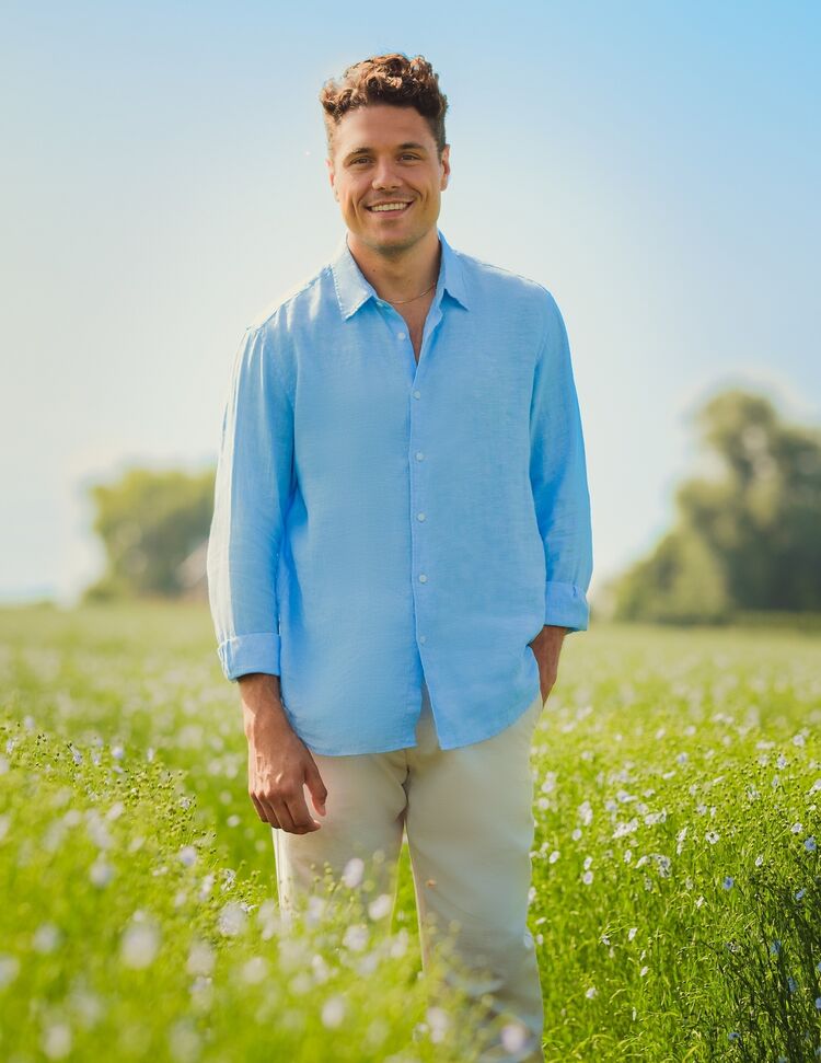 man in flax field wearing linen shirt and linen trousers