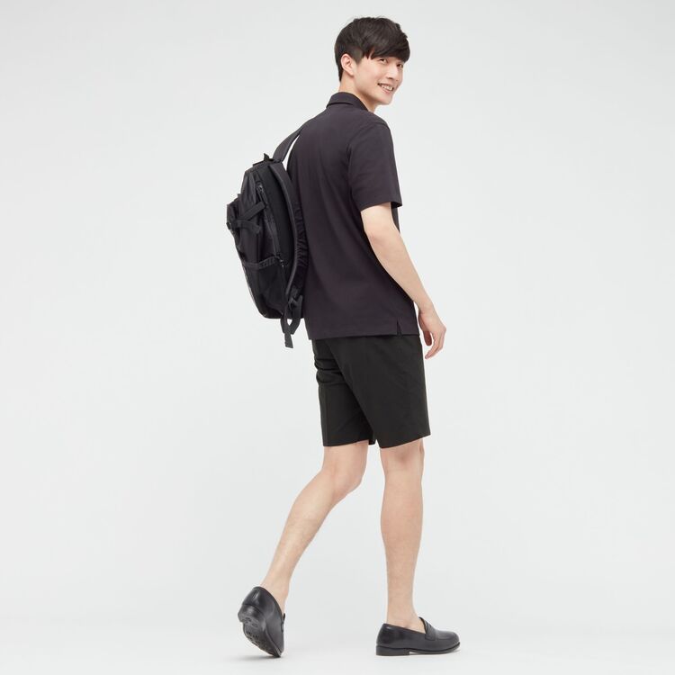 man wearing UNIQLO black polo shirt, black shorts, black backpack, and black loafers