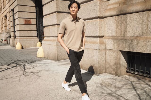 man wearing UNIQLO beige polo shirt and black trousers and white trainers