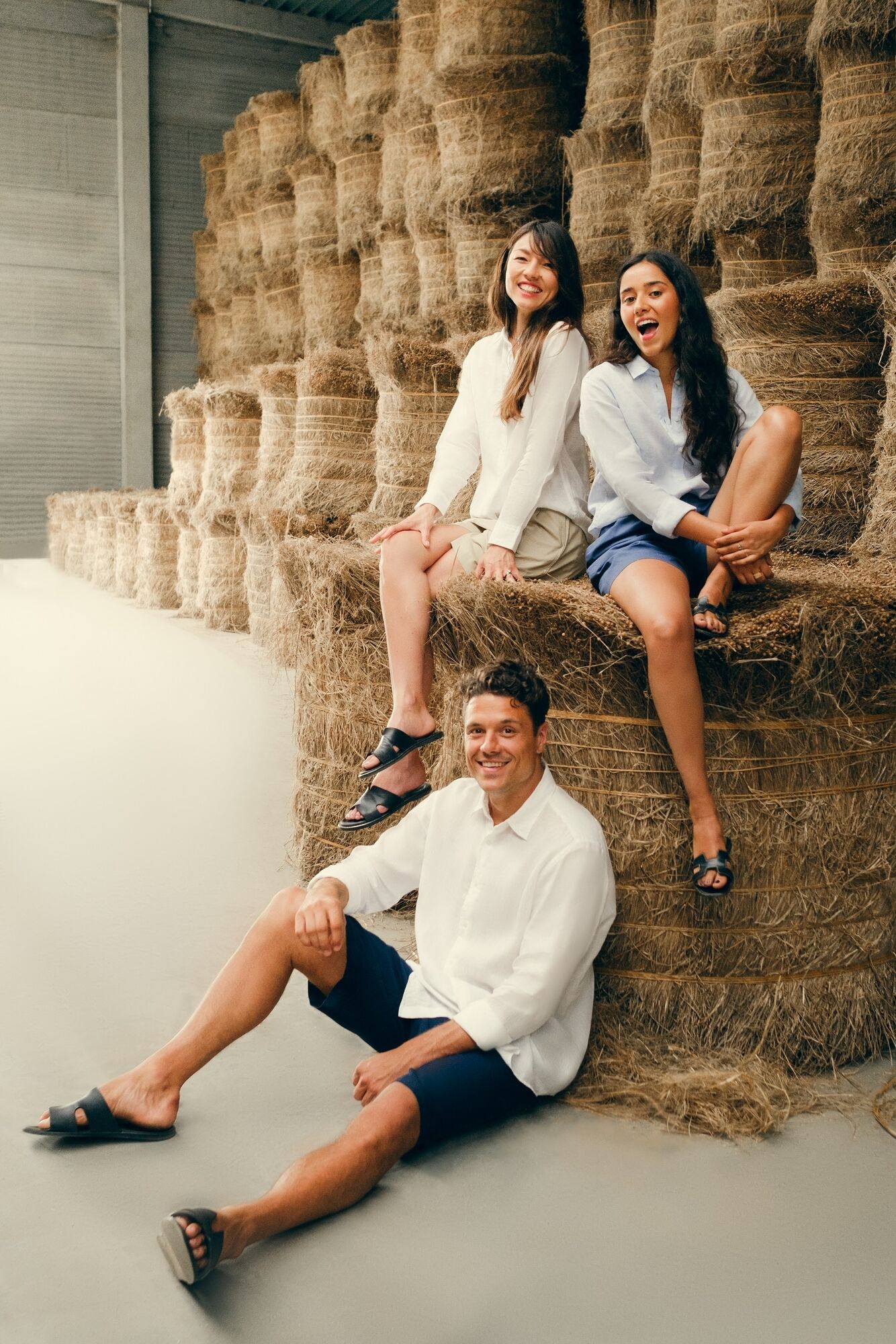 man and women on bales of flax fibre wearing linen clothing