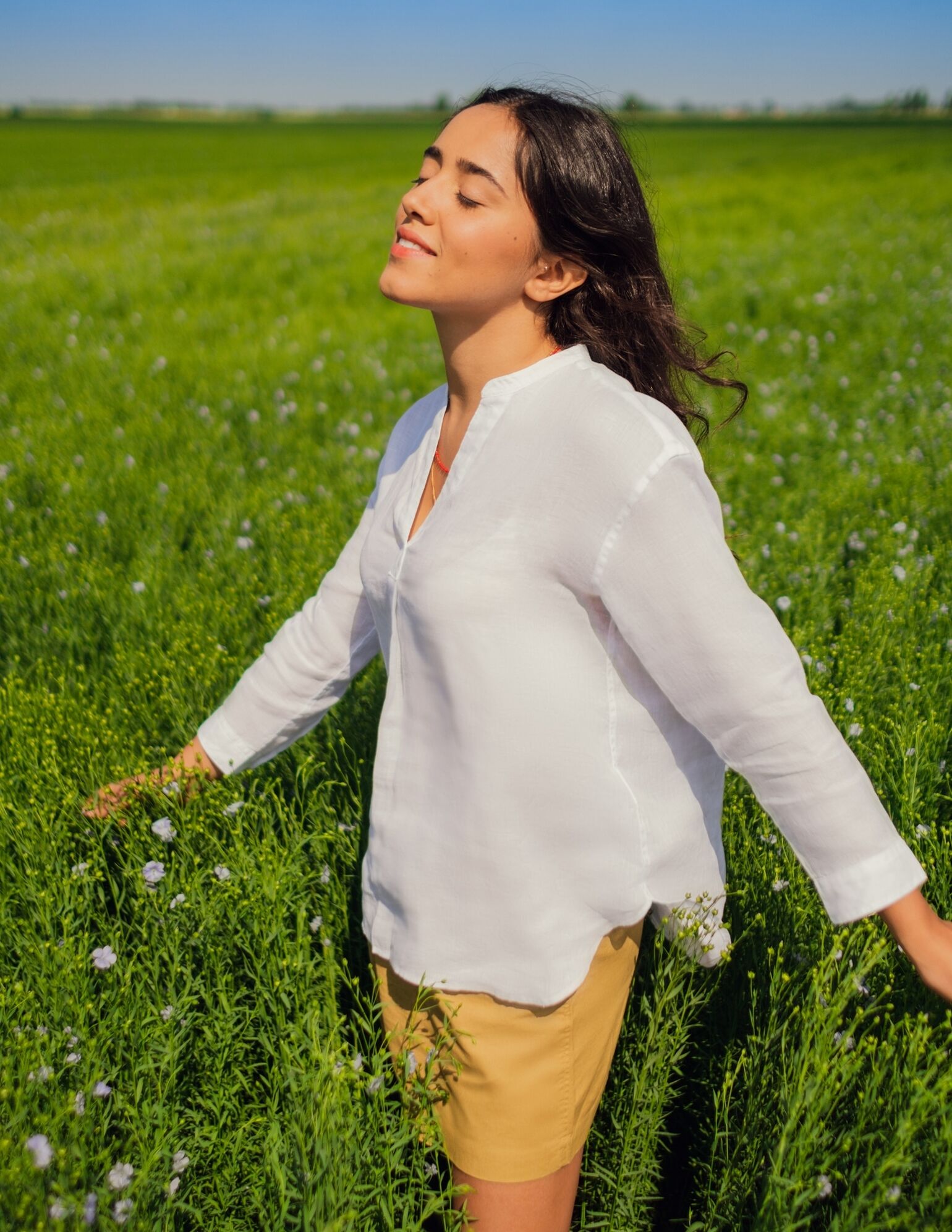 woman in flax field wearing linen clothing