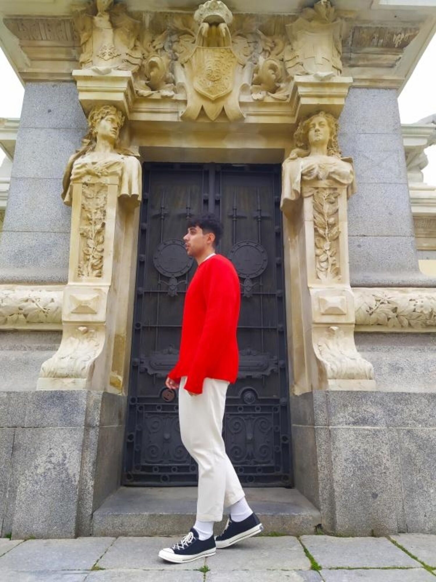 man wearing red jumper and beige trousers