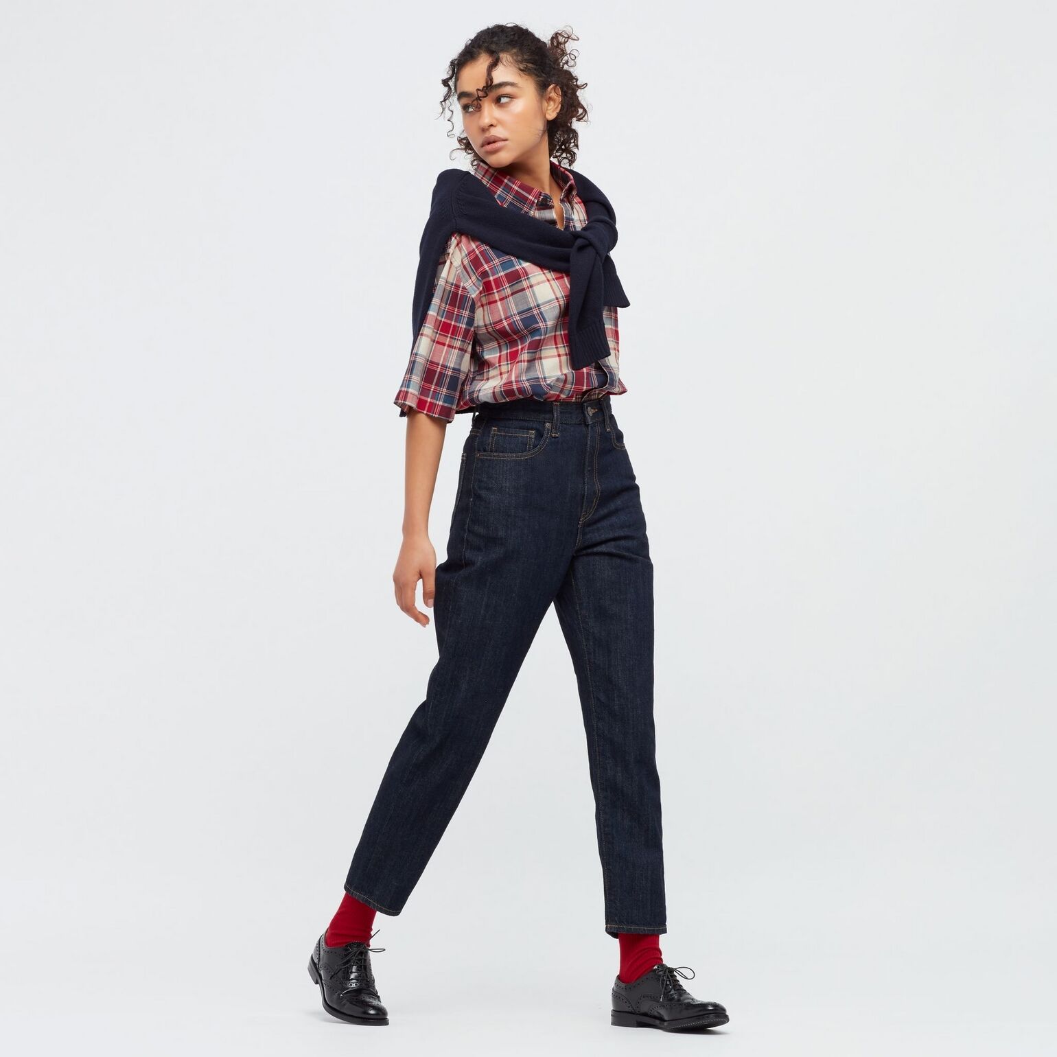 woman wearing UNIQLO mom jeans with checked shirt and jumper draped over shoulders, burgundy socks and brogues