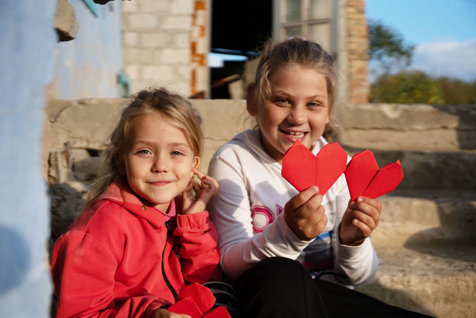 two children holding origami hearts